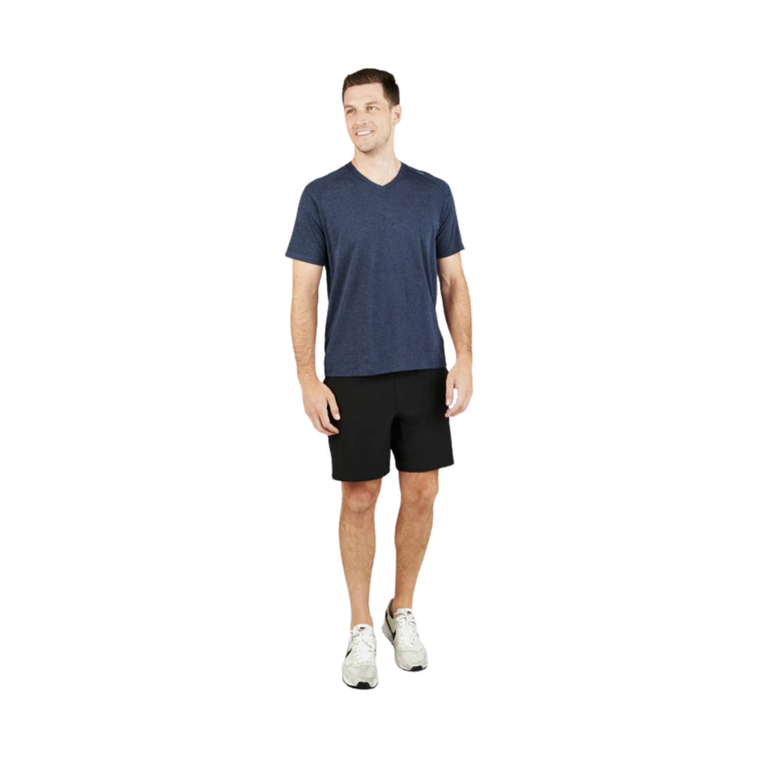 Model wearing a heathered navy V-neck T-shirt with black shorts and white sneakers