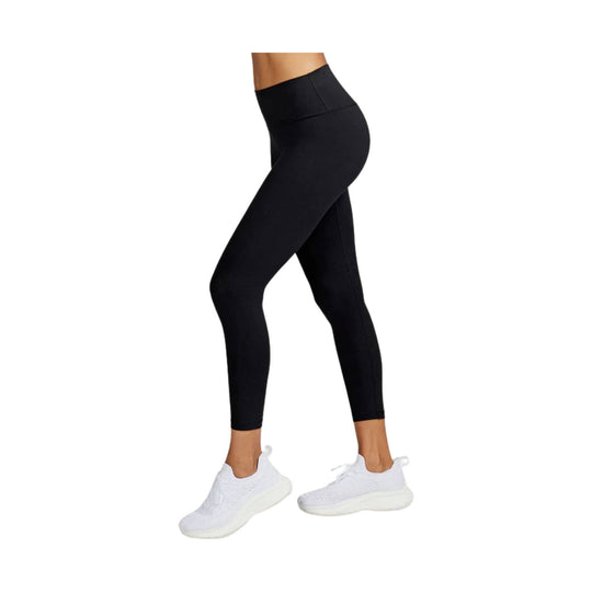 Black high-waisted 7/8 leggings with side pocket detail, worn with white sneakers