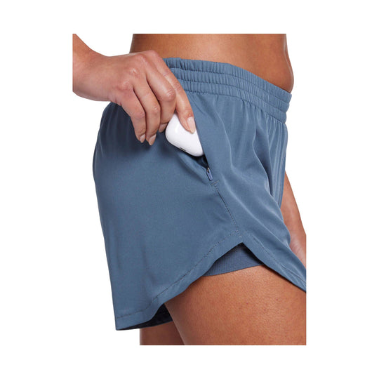 Blue running shorts with a side zipper pocket, shown being held open to reveal a white earbud case.