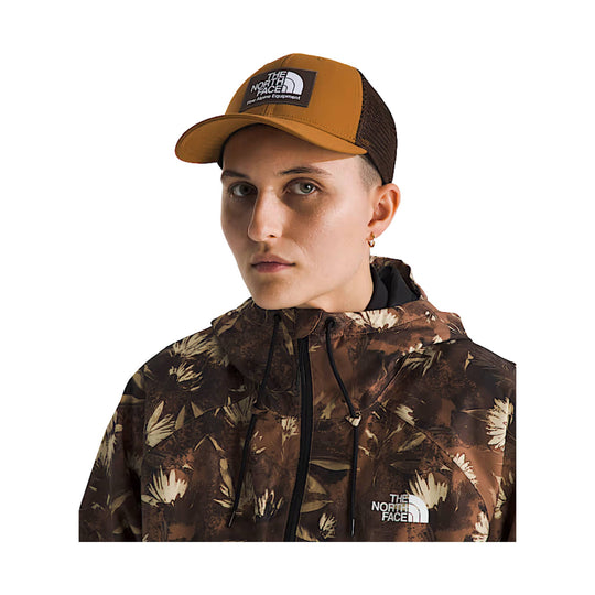 Tan and brown trucker hat with black logo patch and mesh back