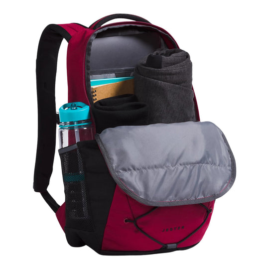Red and black backpack with open front pocket, water bottle, rolled clothing, and visible JESTER text