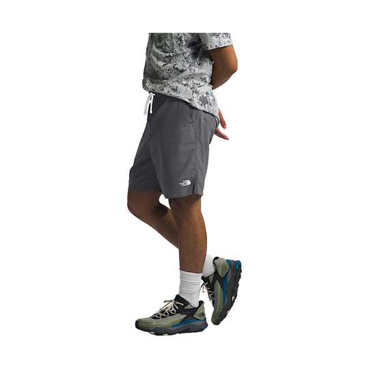 Gray athletic shorts with a small The North Face logo on the leg, shown on a model with a casual tee and trail shoes.