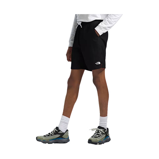 Black athletic shorts with a white logo on the leg, worn with a white long-sleeve top and hiking shoes