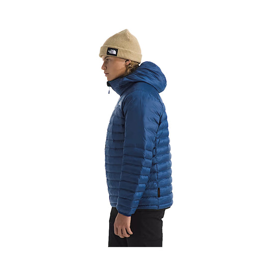 Blue quilted hooded puffer jacket shown in side profile with a tan knit beanie