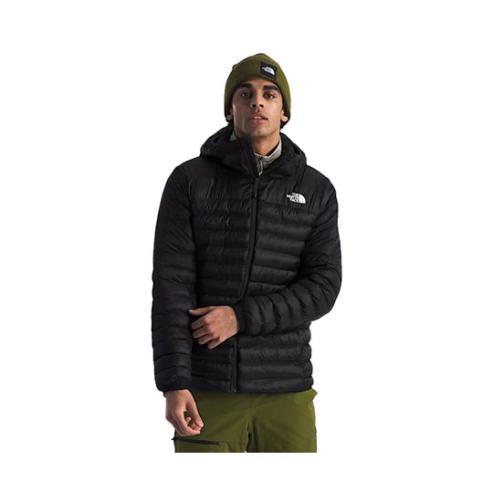 Black hooded puffer jacket with a front zipper and logo on the chest, worn with an olive beanie and pants
