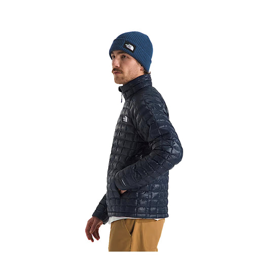 Black quilted puffer jacket with zip-up collar, shown in side profile, worn with a blue knit beanie