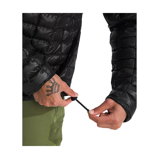 Black quilted puffer jacket with elastic drawcord hem being adjusted by hand