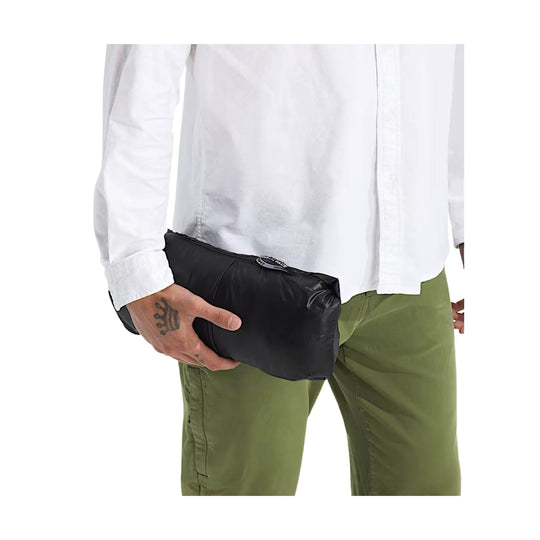 Black puffer jacket folded into a compact pouch and held at the waist