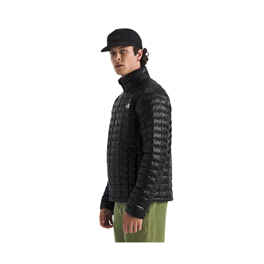 Black quilted puffer jacket worn over olive pants, shown in side profile