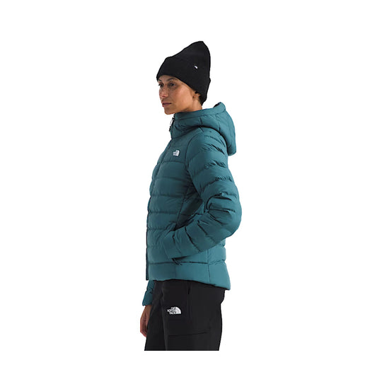Teal hooded puffer jacket worn with hands in pockets, shown in side view