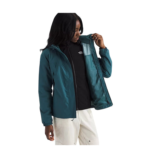 Teal hooded jacket worn over a black zip-up layer with white pants