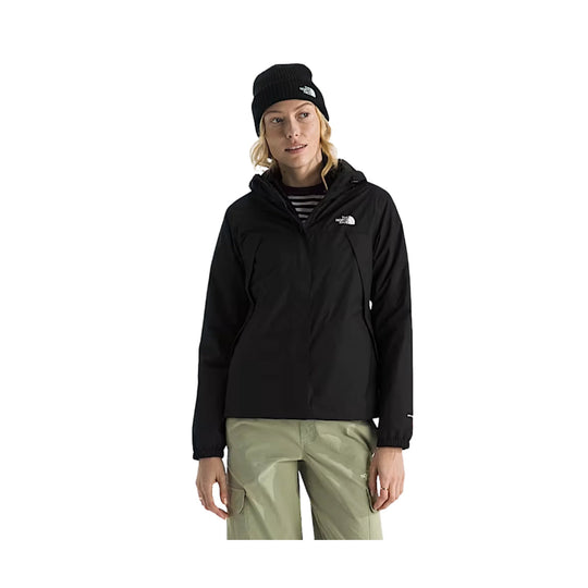 Black hooded jacket with a small white chest logo, worn over a striped top and paired with light cargo pants