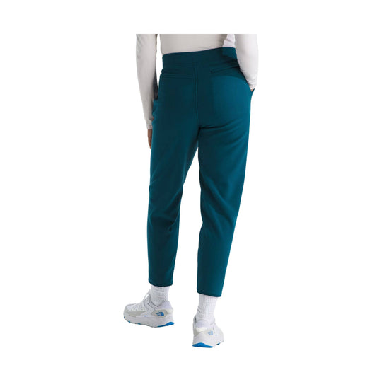 Teal fleece pants shown from the back with tapered legs and white sneakers