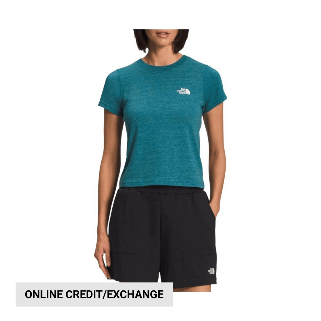 Teal short-sleeve T-shirt with small white chest logo, shown with black shorts on a model