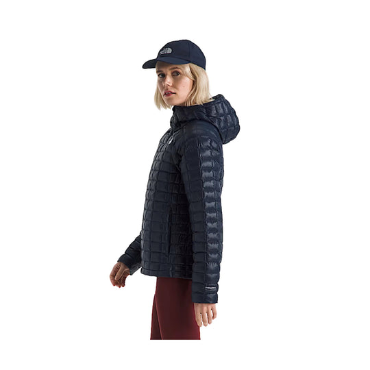 Navy quilted hooded puffer jacket worn with a matching cap, shown in side view