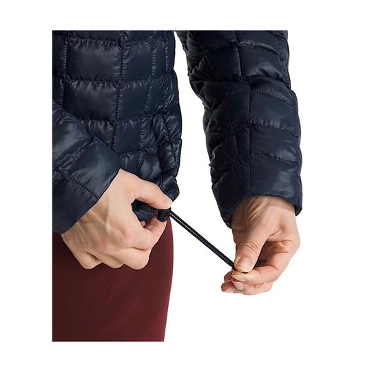 Black quilted puffer jacket sleeve with a hand adjusting the hem drawcord