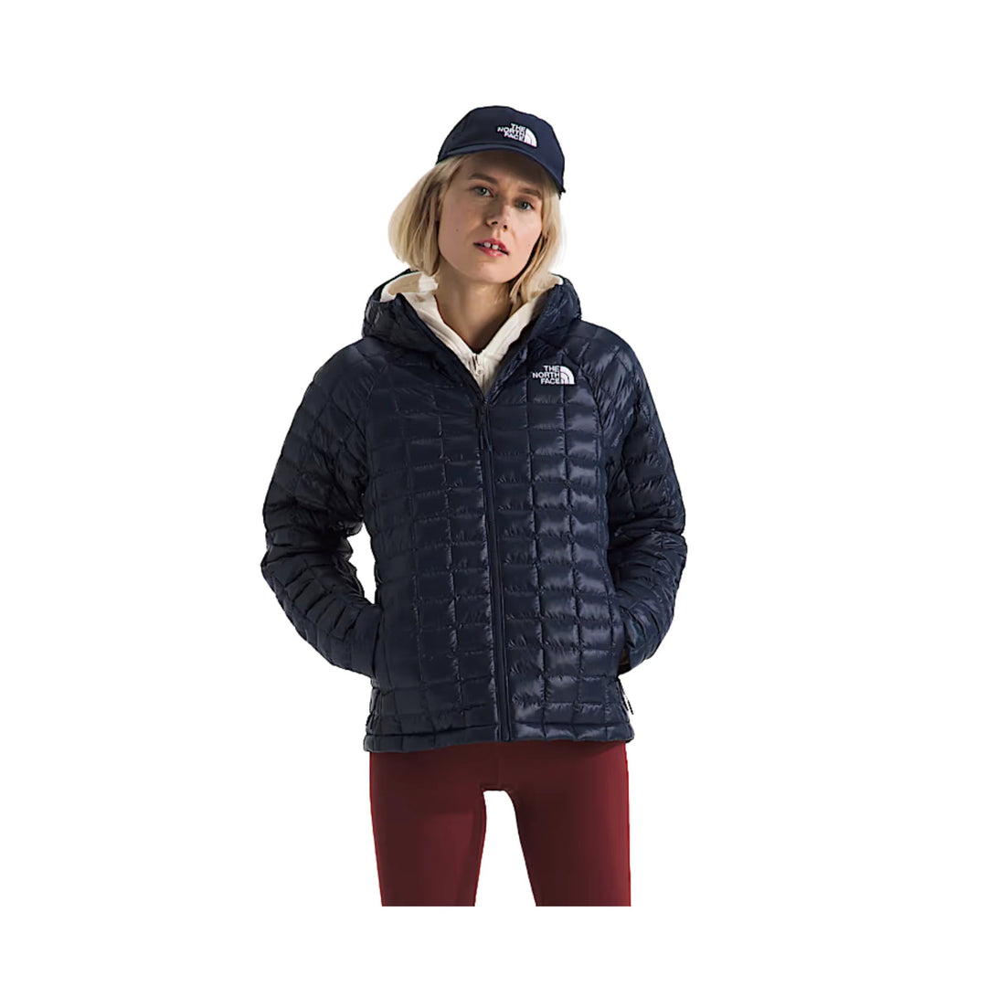 Navy quilted hooded puffer jacket worn with a white layer underneath