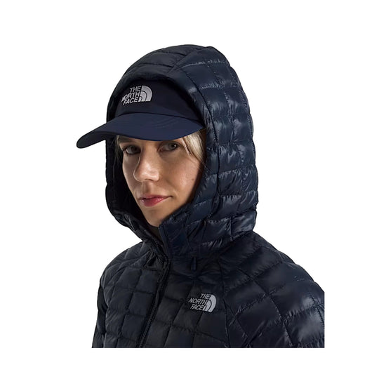 Navy quilted hooded puffer jacket worn with a navy cap, shown front-facing