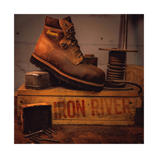 Brown leather lace-up work boot on a wooden crate with visible 'IRON RIVER' text