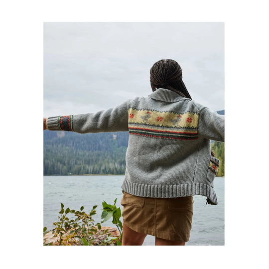 Gray knit cardigan with patterned yoke, striped cuffs and hem, shown from the back outdoors