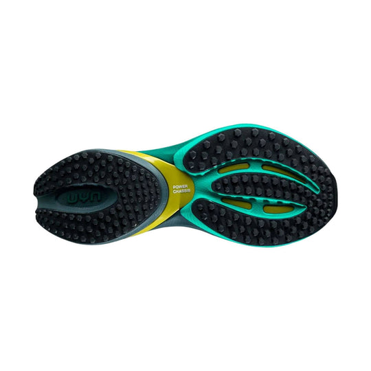 Pair of black shoe outsoles with teal and yellow midfoot panels and hexagonal tread