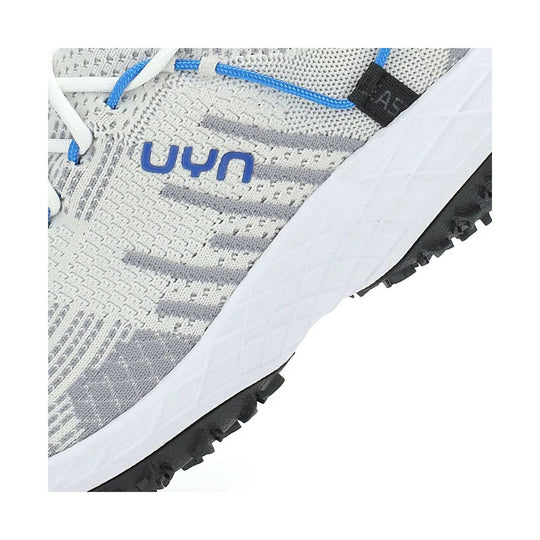 White and gray knit trail shoe with blue laces, black lug sole, and visible UYN branding