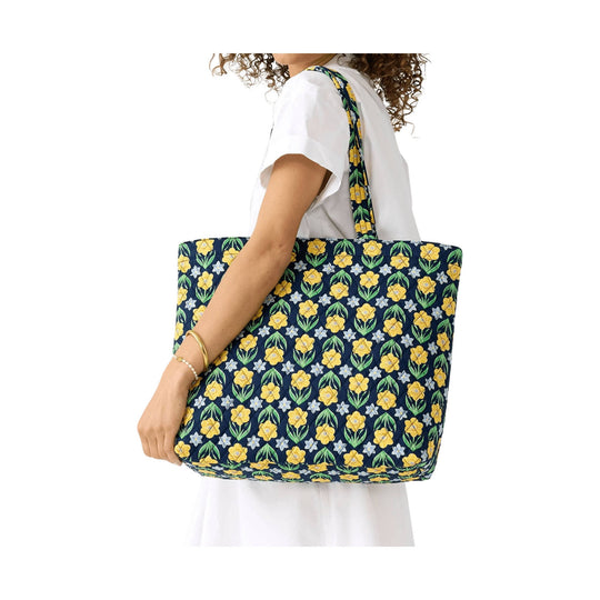 Large navy floral tote bag with yellow and green daffodil print, shown on a model's shoulder.