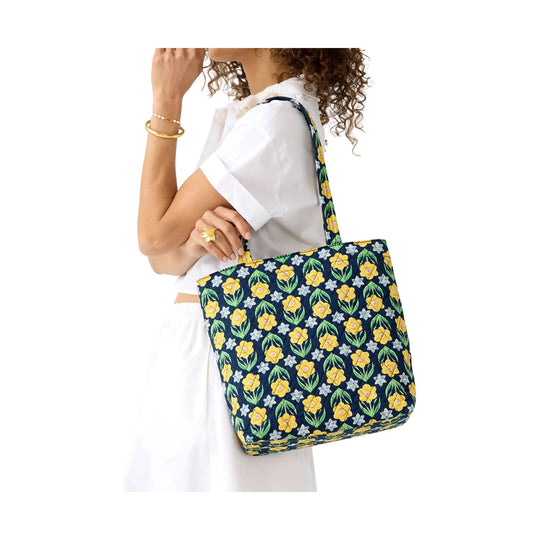Navy tote bag with yellow and light blue floral print, shown on a model's shoulder.