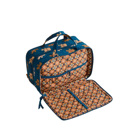 Blue quilted travel case with tan patterned lining, handles, and multiple zippered compartments, shown open