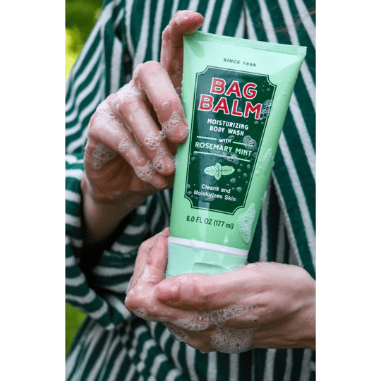 Mint green body wash tube with dark green label, shown in soapy hands