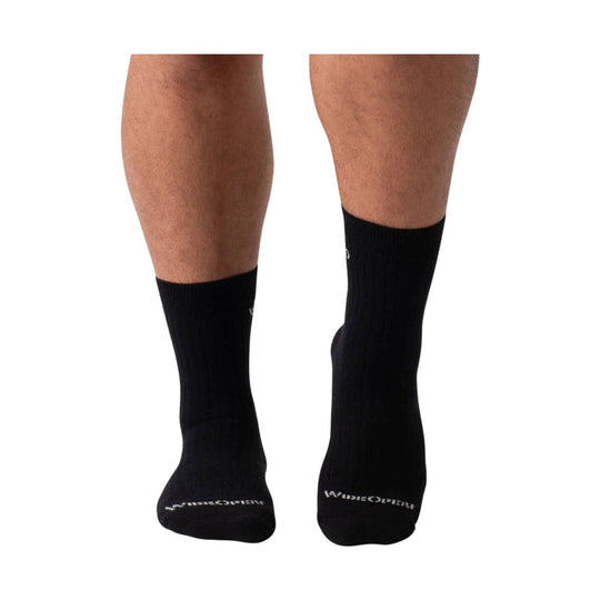 Black ribbed crew socks worn on lower legs, with white logo text on the soles