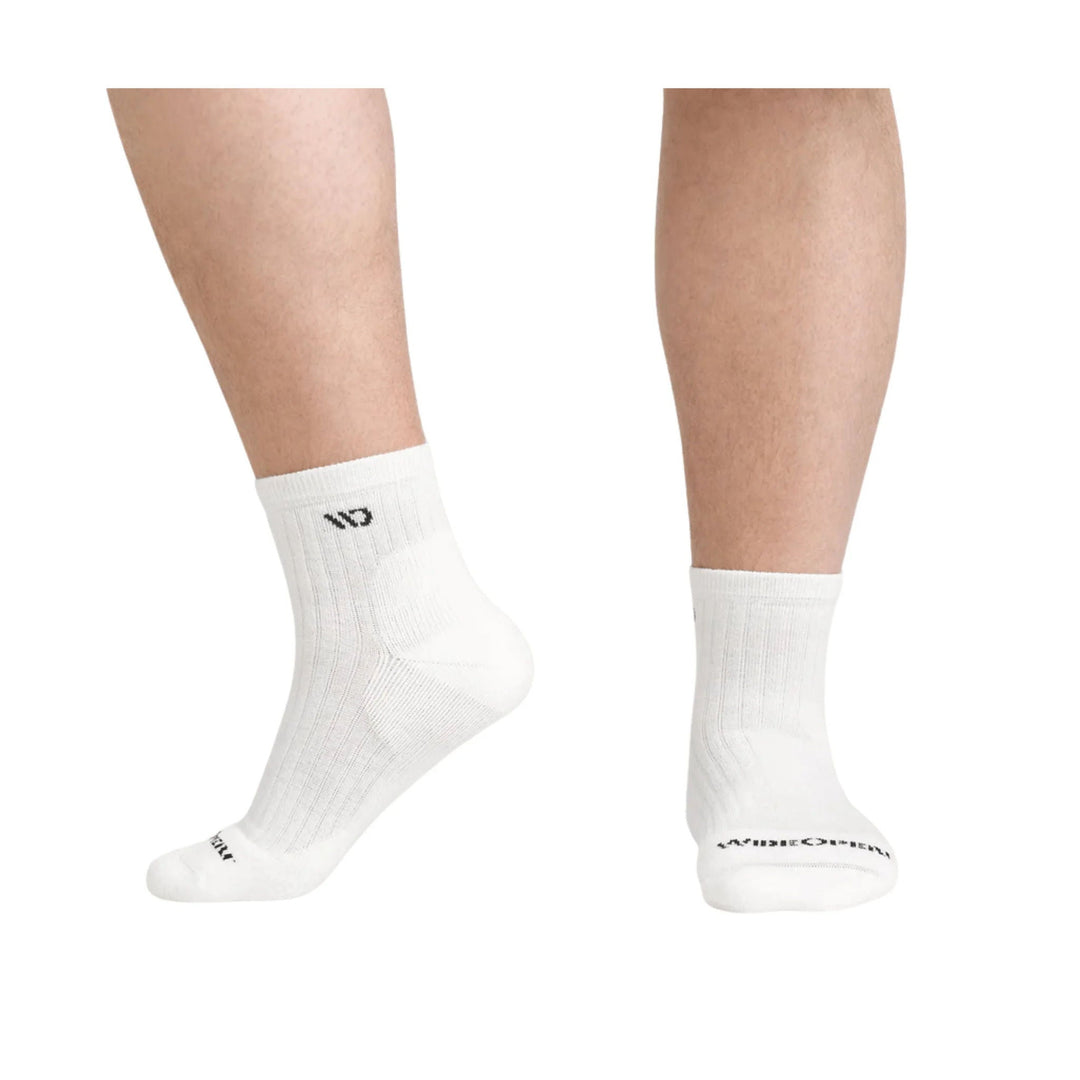 White quarter socks on a model’s lower legs, with ribbed cuffs and black logo text near the toes.