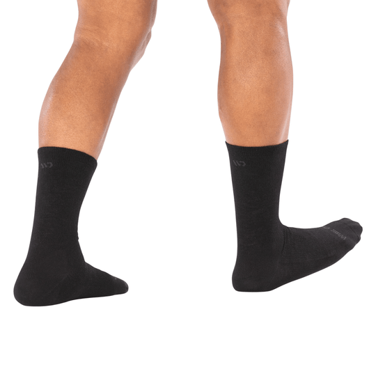 Black crew socks on a model's lower legs and feet, shown in side view with one foot flexed.