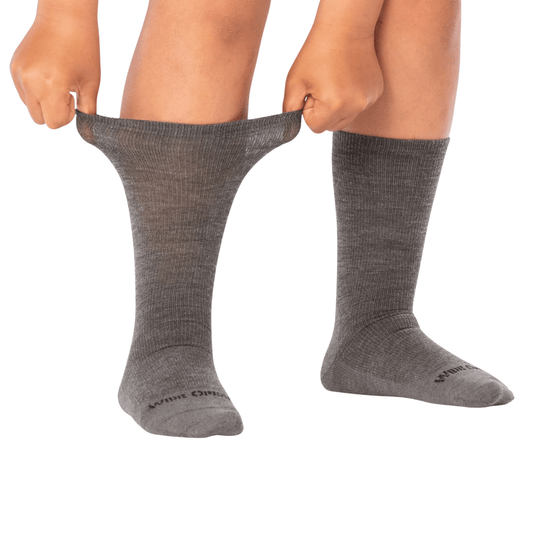 Gray ribbed crew socks shown on legs, with one sock pulled off and stretched by hand