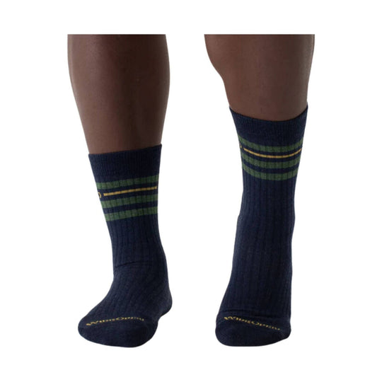 Pair of navy crew socks with green and yellow horizontal stripes on the cuffs, shown on a model's lower legs.