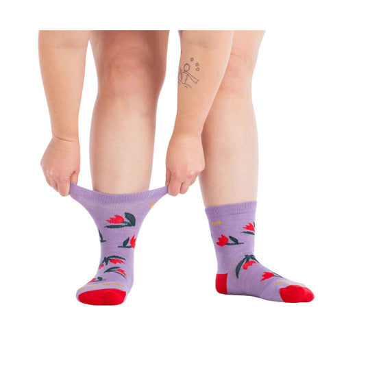 Lavender crew socks with red tulip and green leaf pattern, shown being stretched on a model