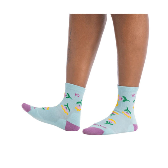 Light blue crew socks with pink toe and heel, green stems, and yellow and pink floral pattern on a model’s legs.