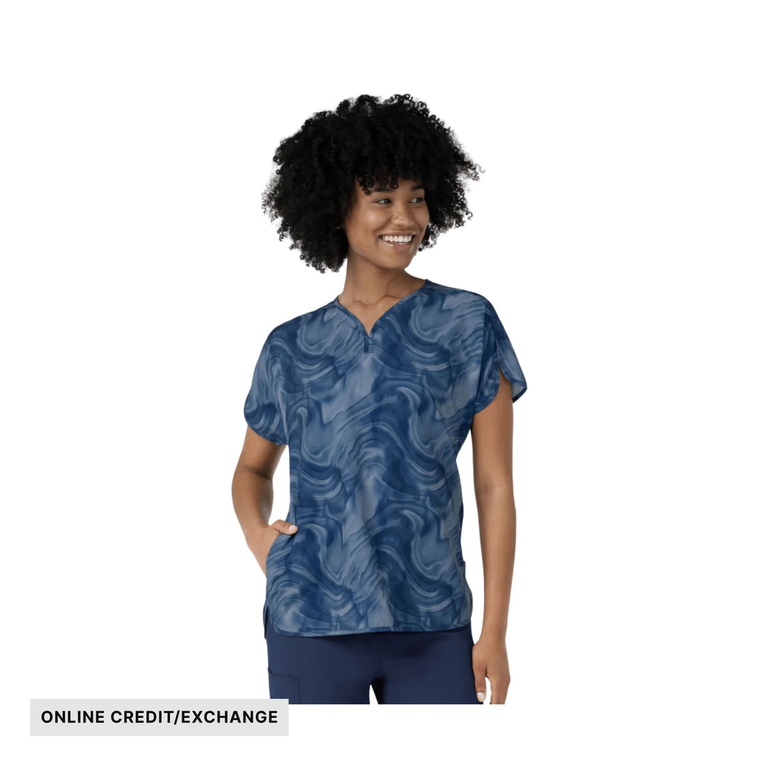 Blue patterned dolman scrub top on a model with a V-neck and short sleeves