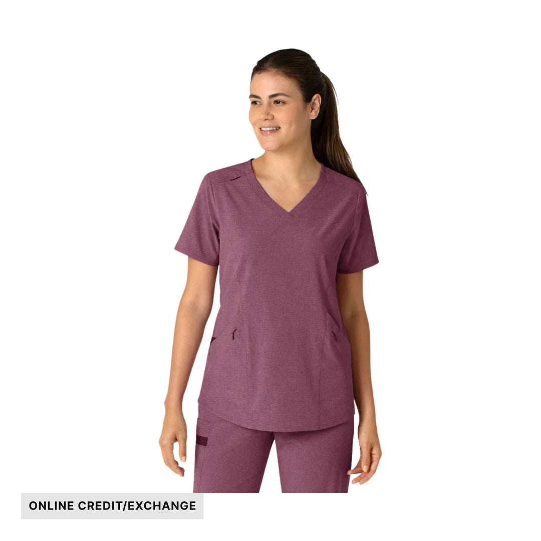 Woman wearing a heathered burgundy V-neck scrub top and pants with pockets; “ONLINE CREDIT/EXCHANGE” label