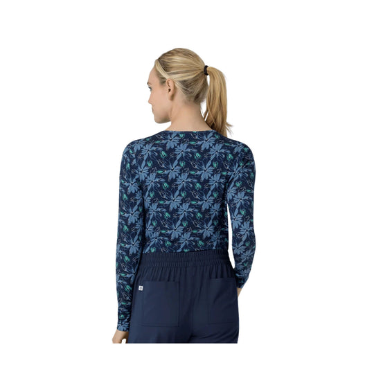 Woman wearing a navy long-sleeve floral scrub top with matching navy pants, shown from the back.