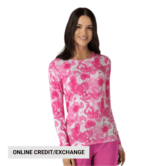 Pink and white long-sleeve scrub top with heart pattern on a model, with “ONLINE CREDIT/EXCHANGE” text overlay