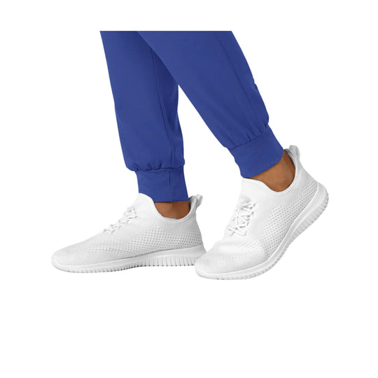 White knit jogger sneakers with ribbed soles, shown with blue cuffed pants