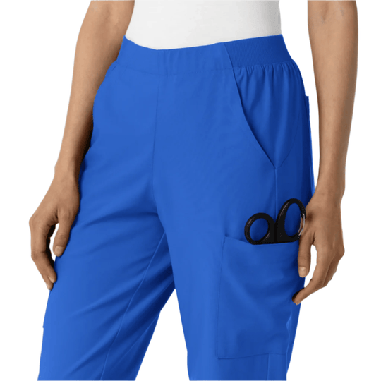Blue cargo scrub pants with elastic waistband and side pocket holding scissors