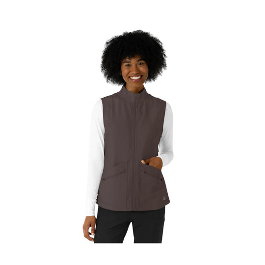Women’s brown zip-front scrub vest with chest pockets, worn over a white long-sleeve top