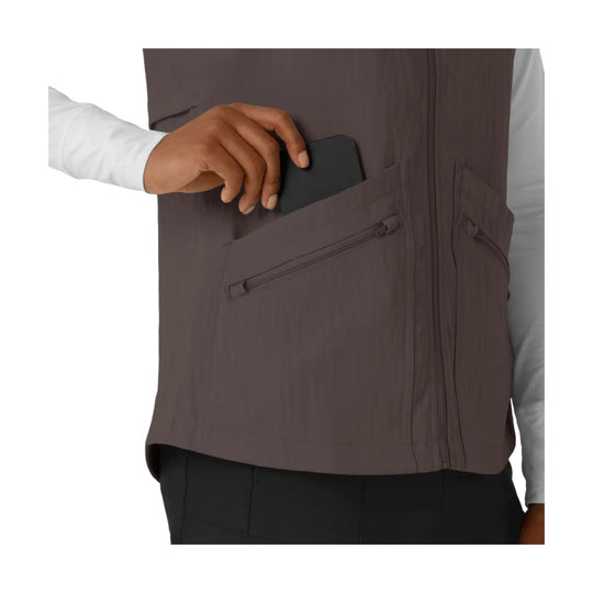 Brown zip-front scrub vest with chest and side pockets, shown over a white long-sleeve shirt.