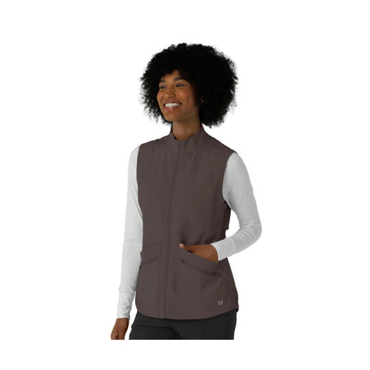 Brown zip-front scrub vest with side pockets, worn over a light long-sleeve top