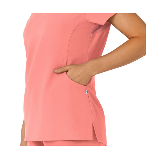Coral pink V-neck scrub top with chest seam detailing, side pocket, and side slits