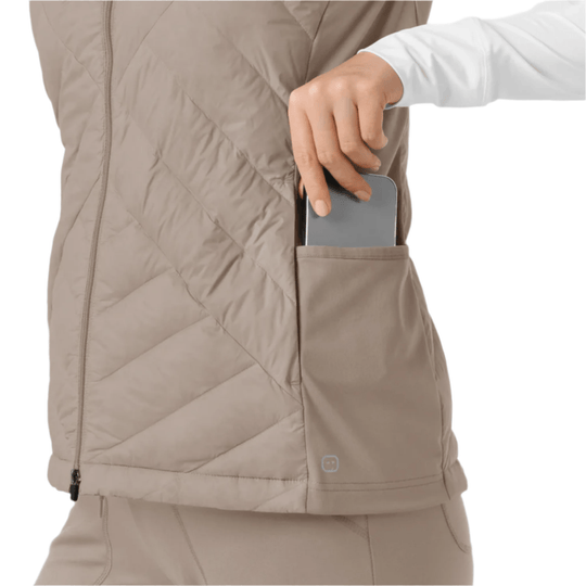 Beige quilted vest with zip front and side pocket holding a phone