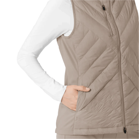 Beige quilted zip-front vest layered over a white long-sleeve top, cropped at the torso
