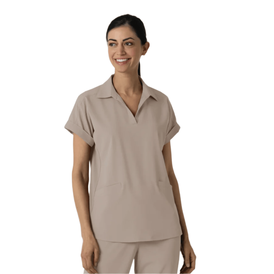 Beige short-sleeve V-neck scrub top with rolled cuffs and chest pockets, shown on a model